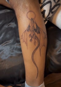a tattoo of a dragon on a person's leg