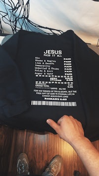 a person is holding up a black sweatshirt that says jesus